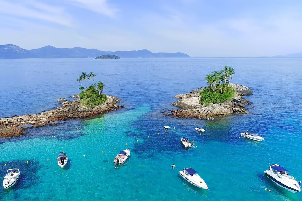 Aerial view of small tropical islands with palm trees surrounded by crystal-clear turquoise waters, with boats anchored nearby