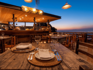 Rustic open-air restaurant in Brazil with a stunning sunset view, wooden tables, and elegant table settings.